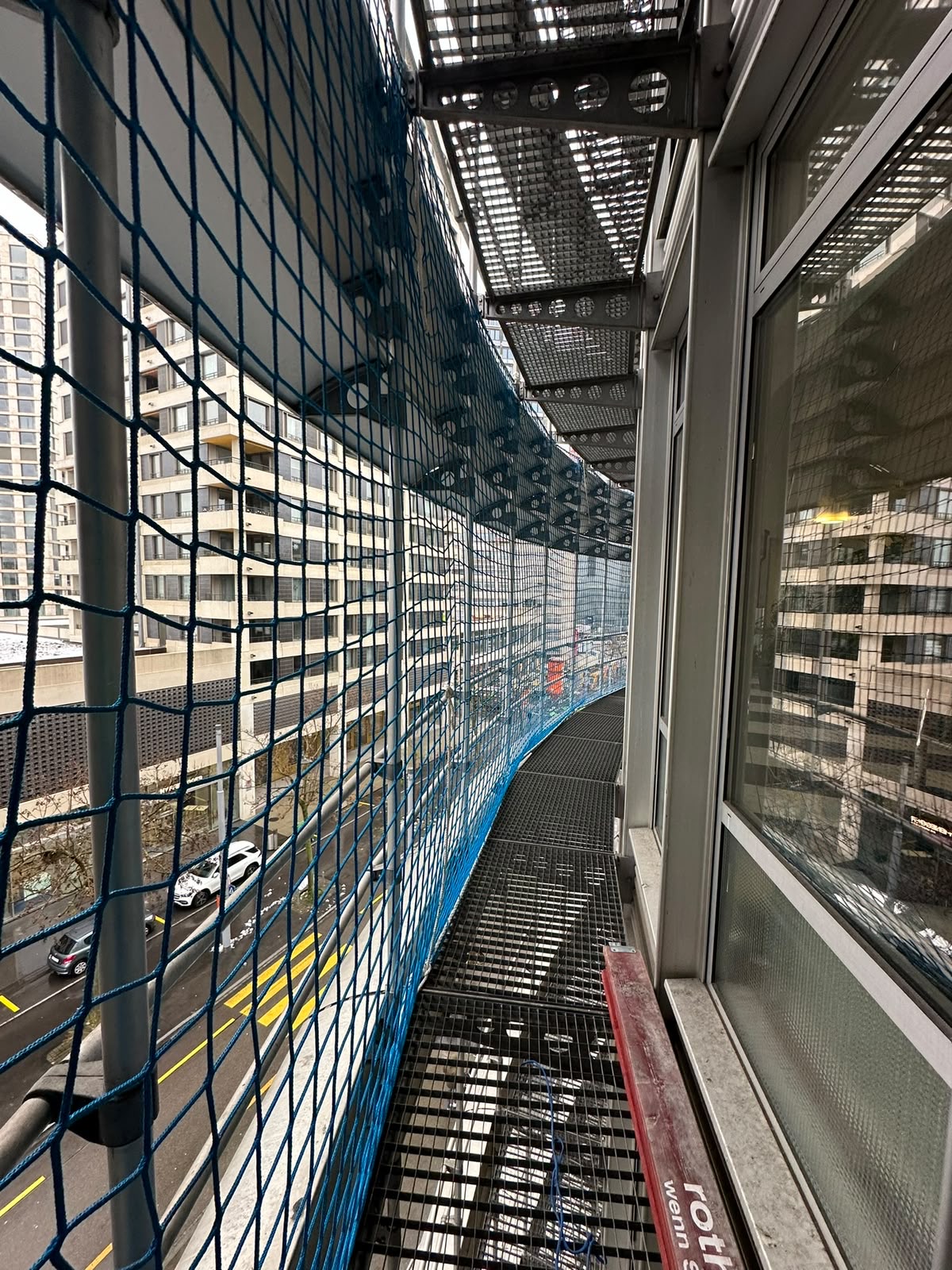 Fassadennetz an einem Hochhaus über der Strasse